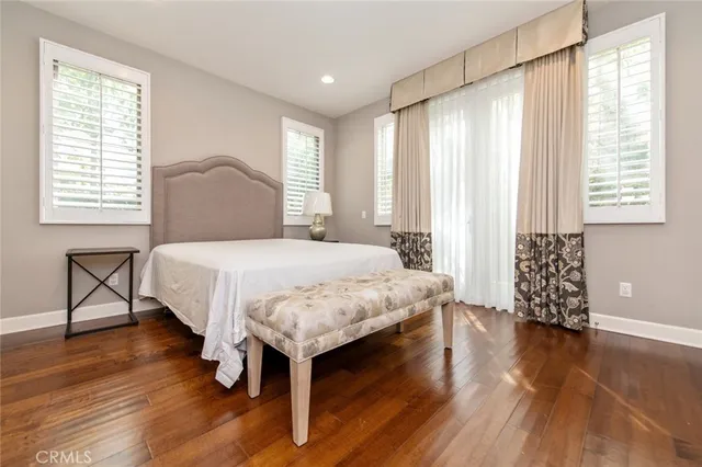 a bedroom with a bed a table and wooden floor