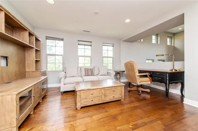a living room with furniture and a dining table with wooden floor
