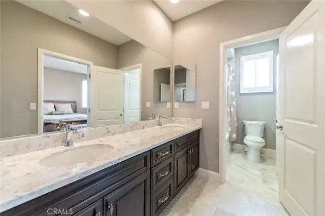a bathroom with a granite countertop sink a toilet and a large mirror