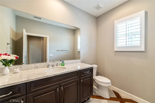 a bathroom with a granite countertop sink a toilet and a mirror