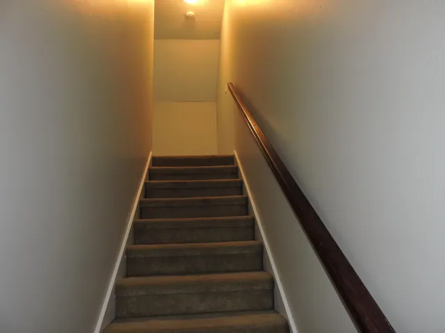 an empty room with a chandelier fan and windows
