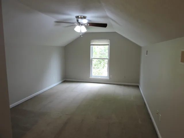 an empty room with a fan and a window