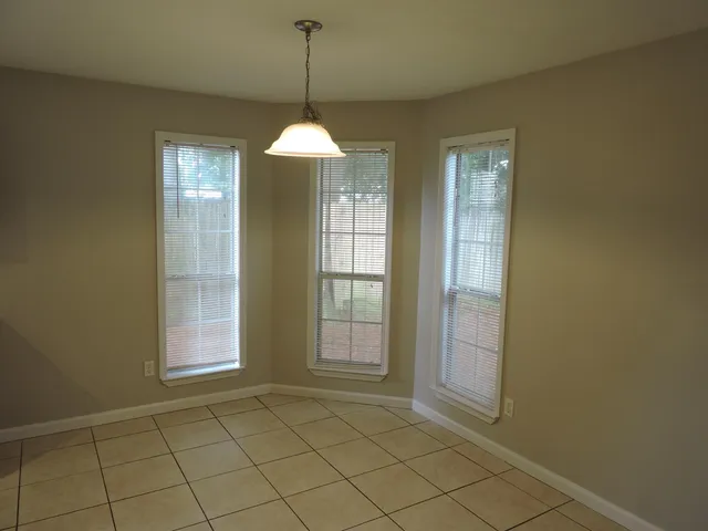 a view of an empty room with window and chandelier fan