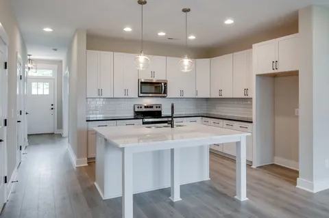 a large kitchen with stainless steel appliances kitchen island a stove a refrigerator a center island and wooden floor