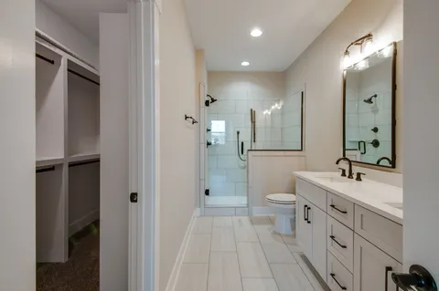 a bathroom with a double vanity sink toilet mirror and shower