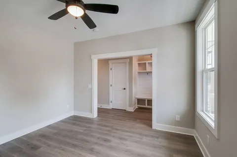 an empty room with wooden floor fan and windows