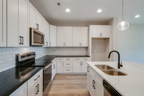 a kitchen with granite countertop a sink a stove and cabinets