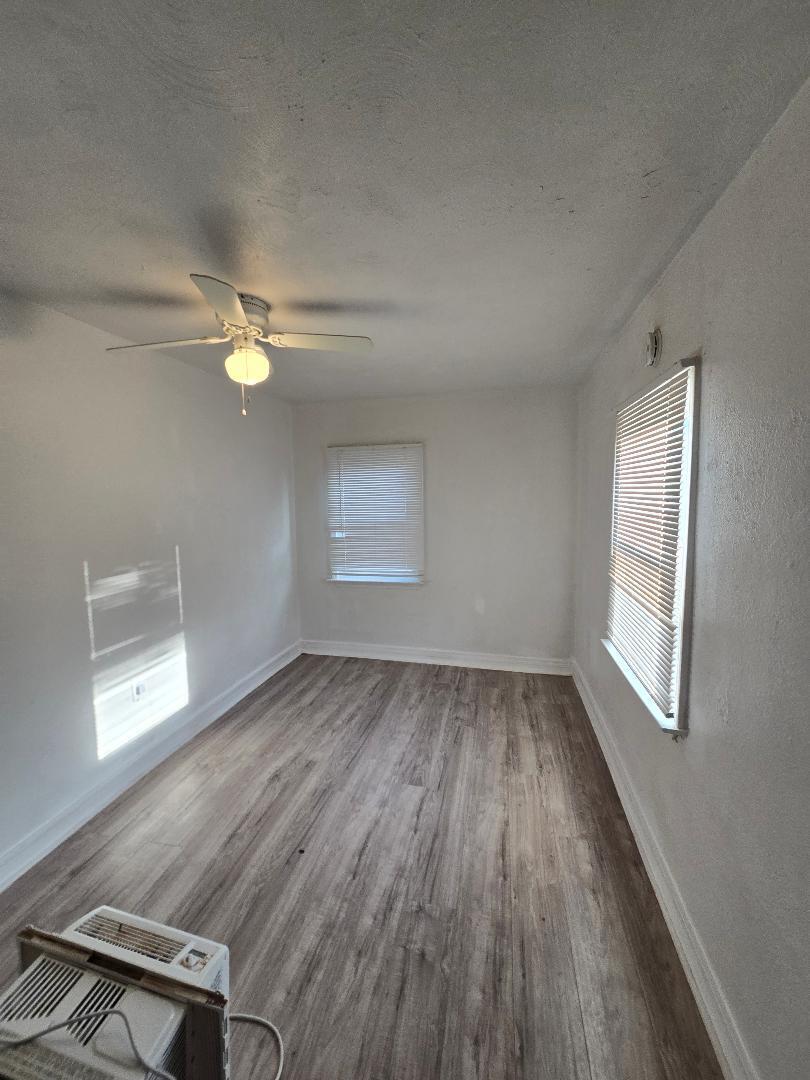 702 North Ave O Lamesa, TX 79331 - Photo 6 of 12 an empty room with wooden floor fan and windows