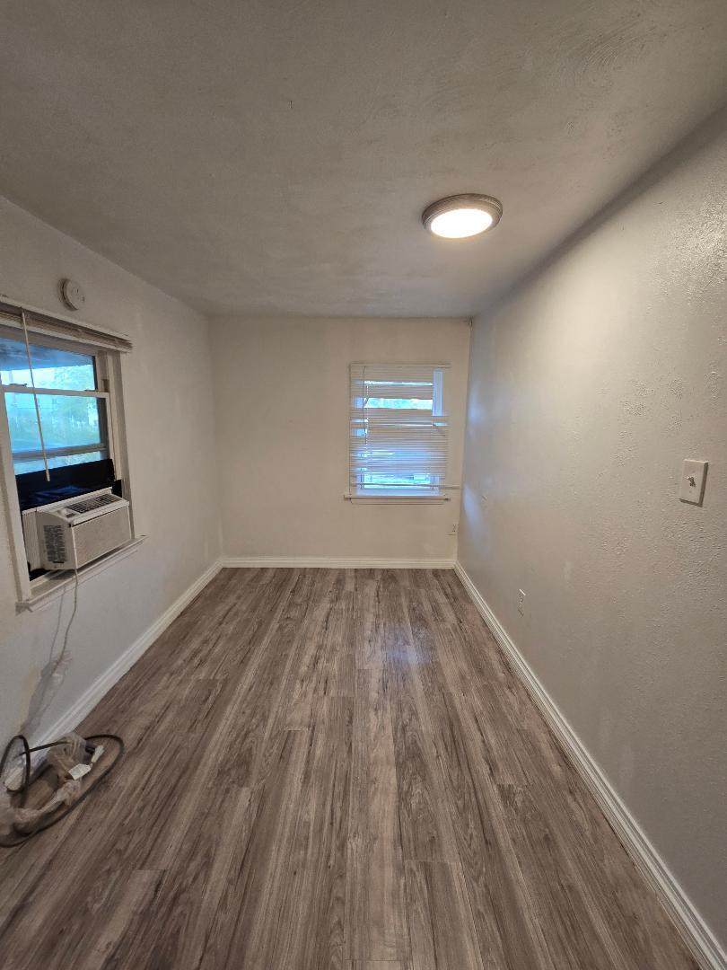 702 North Ave O Lamesa, TX 79331 - Photo 7 of 12 an empty room with wooden floor and windows