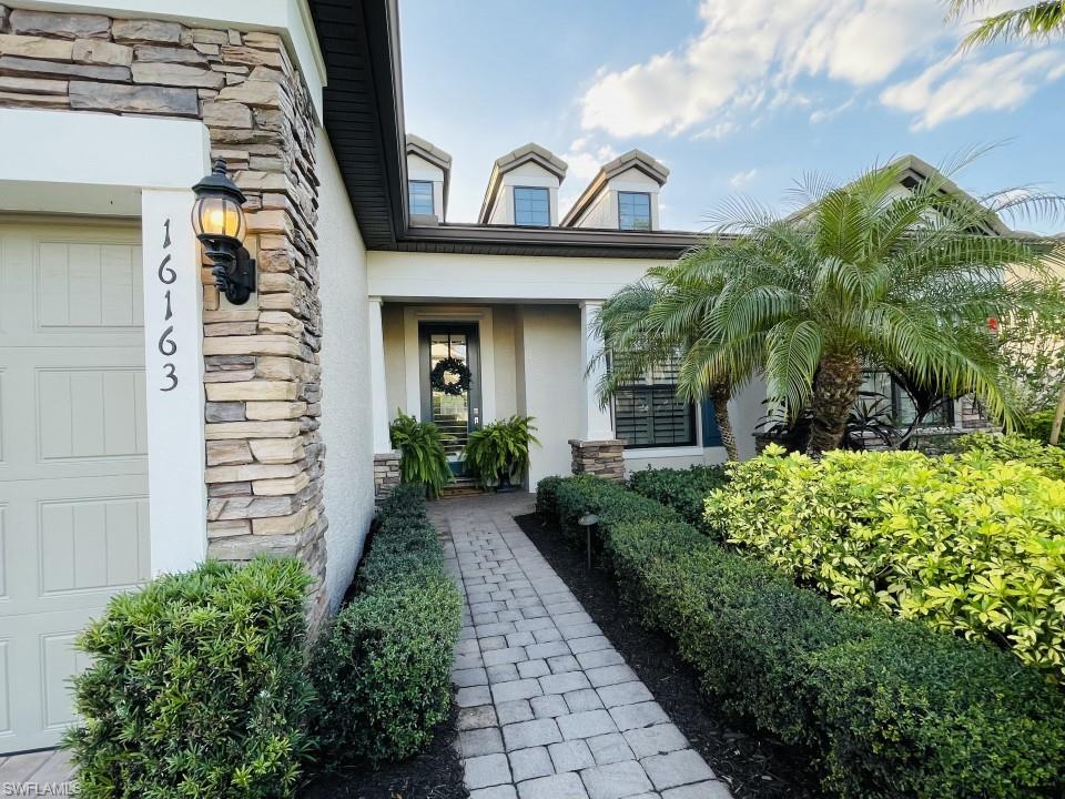 16163 Cartwright Lane Naples, FL 34110 - Photo 3 of 35 a view of a house with a small yard plants and a fountain