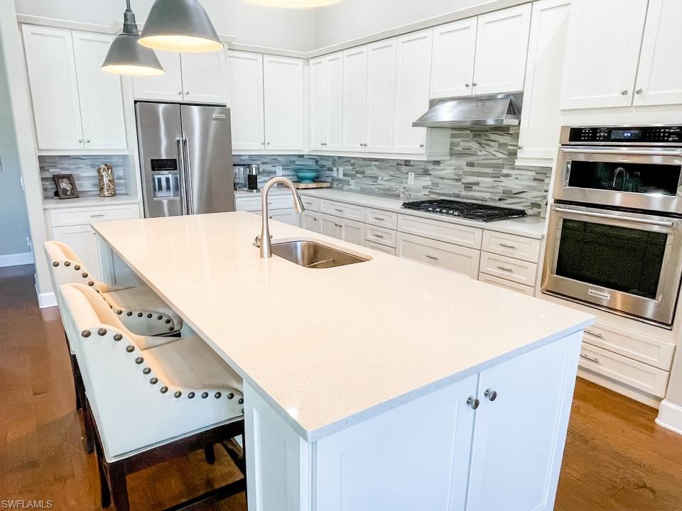 16163 Cartwright Lane Naples, FL 34110 - Photo 10 of 35 a kitchen with stainless steel appliances a stove a sink a microwave and cabinets