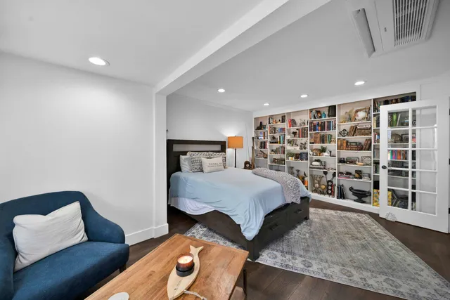 a bedroom with a bed and a bookshelf with wooden floor