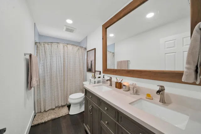 a bathroom with a double vanity sink toilet and a mirror