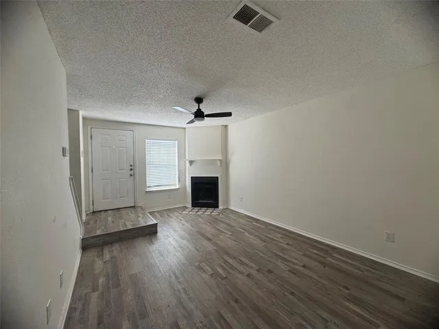 an empty room with wooden floor fireplace and windows