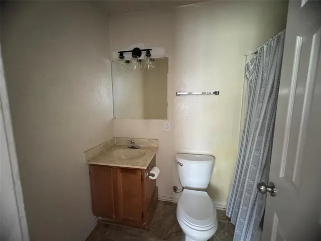 a bathroom with a granite countertop toilet and a sink