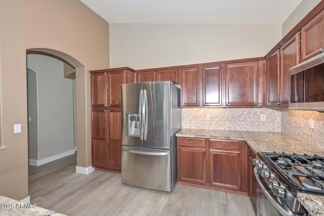 a kitchen with granite countertop a refrigerator and a stove top oven