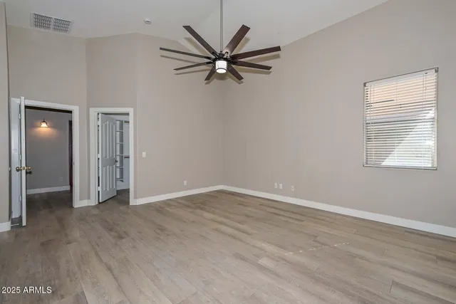an empty room with wooden floor and a ceiling fan