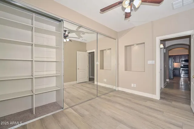 a view of empty room with wooden floor and fan
