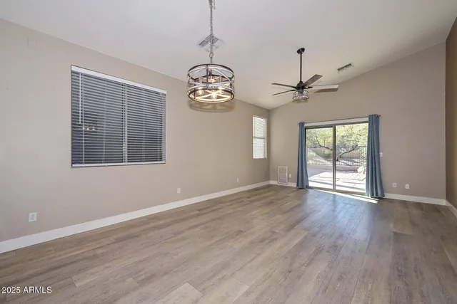 a view of an empty room with wooden floor and window