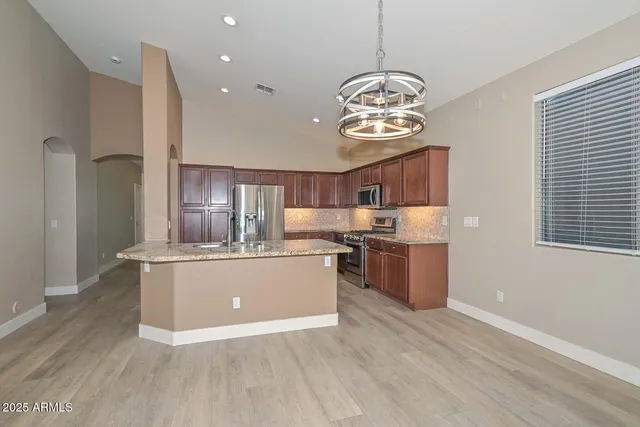 a view of kitchen with stainless steel appliances granite countertop stove and wooden floor