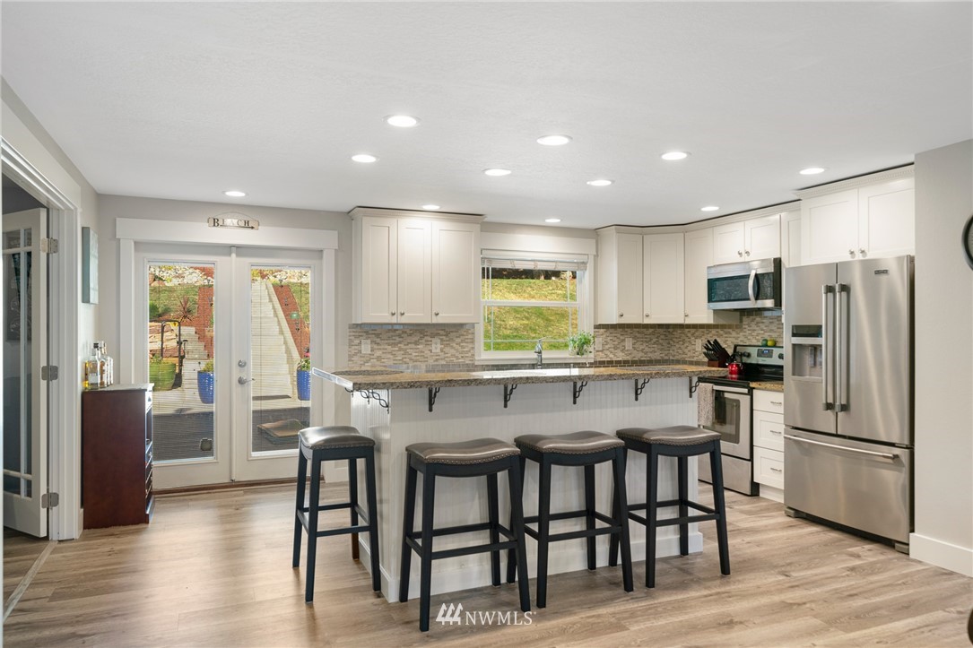 23019 19th Drive Southeast Bothell, WA 98021 - Photo 7 of 28 a kitchen with stainless steel appliances granite countertop a dining table chairs refrigerator and sink
