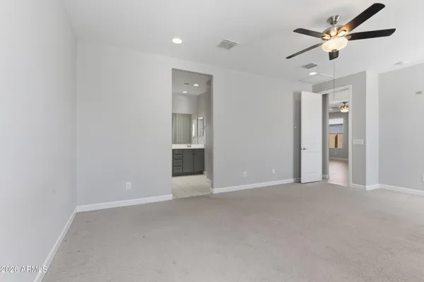an empty room with chandelier fan and windows