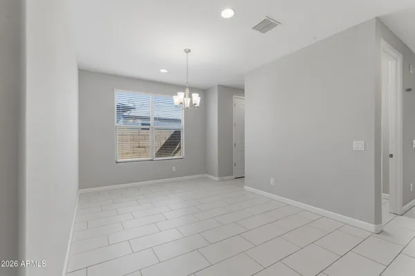 an empty room with chandelier fan and windows