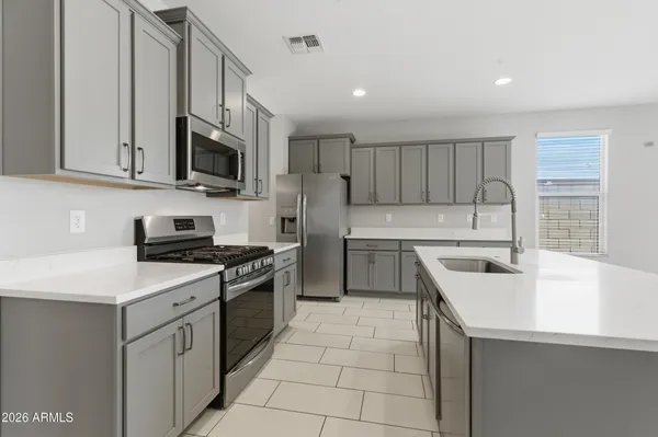 a kitchen with stainless steel appliances a sink stove top oven and white cabinets