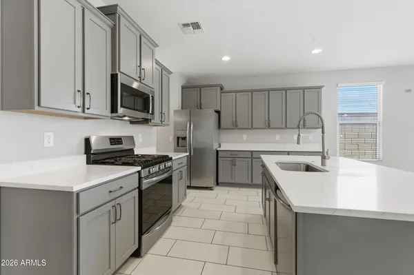 a kitchen with stainless steel appliances a sink stove top oven and white cabinets