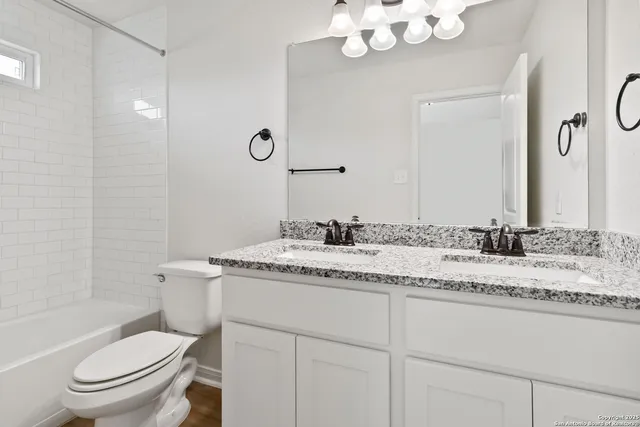 a bathroom with a granite countertop sink a toilet and a mirror