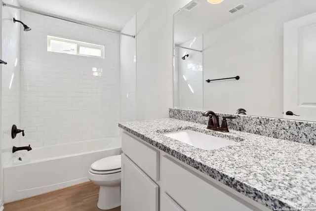 a bathroom with a granite countertop sink a toilet and bathtub
