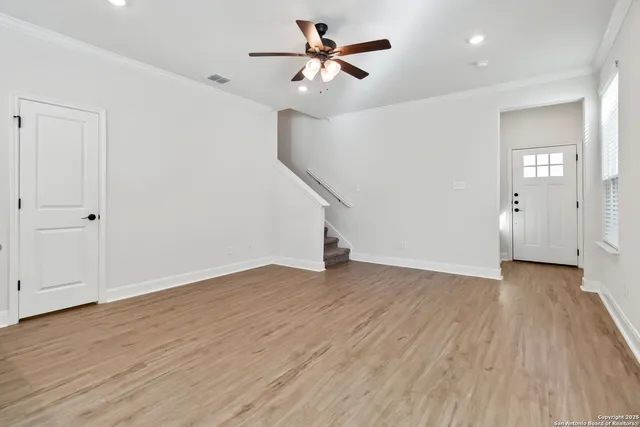a view of empty room with wooden floor and fan