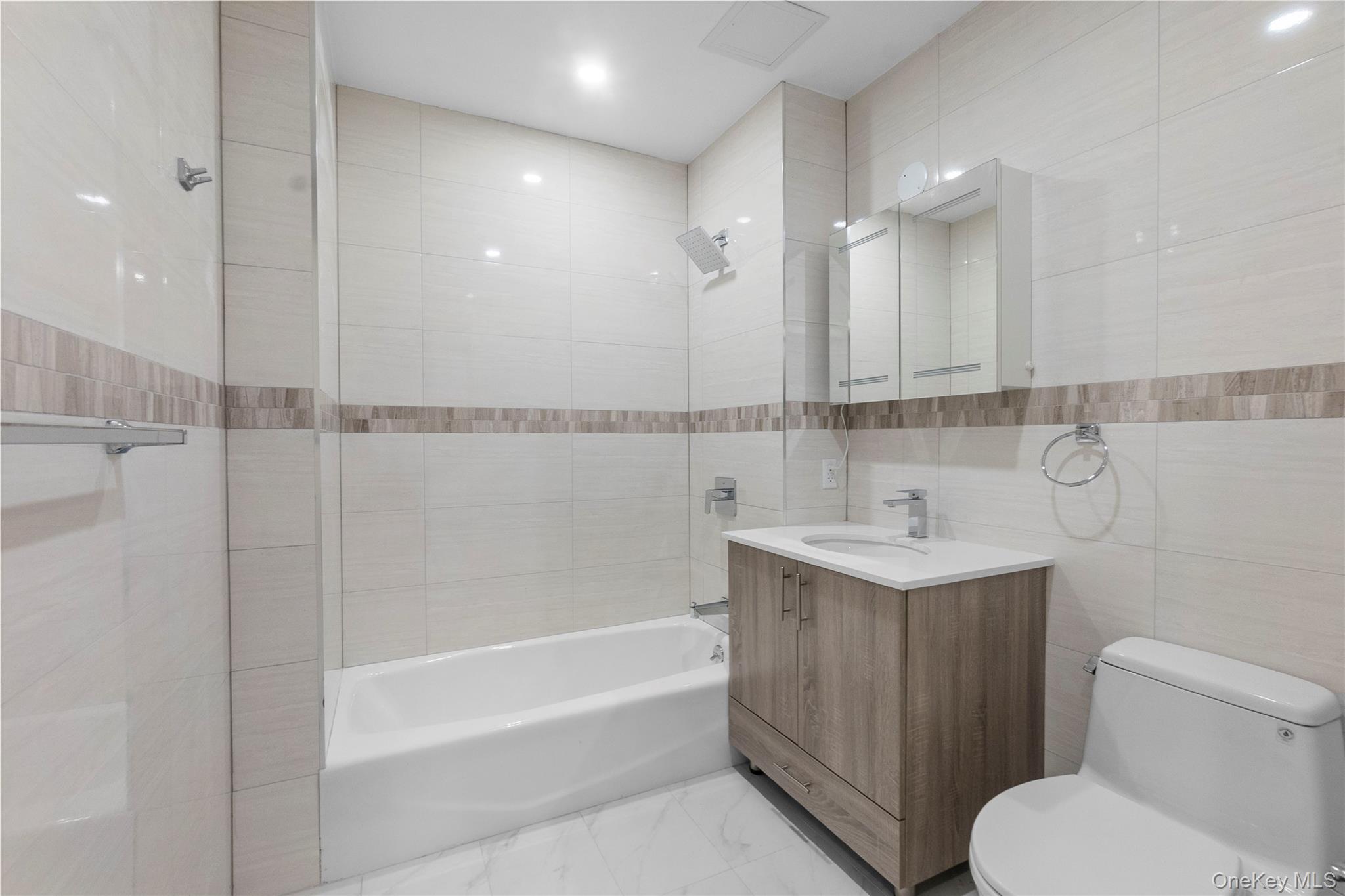 124-28 Queens Boulevard, Unit 10C Queens, NY 11415 - Photo 11 of 14 Bathroom featuring tile walls, shower / washtub combination, vanity, and light marble finish floors