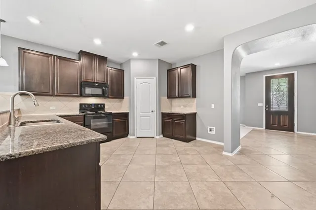 an empty room with chandelier fan and windows