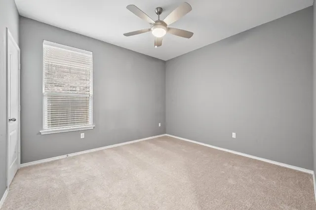 an empty room with windows and ceiling fan