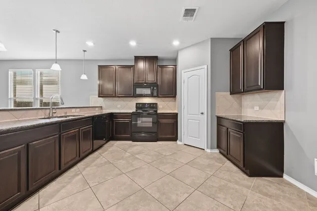 a view of an empty room with kitchen and window