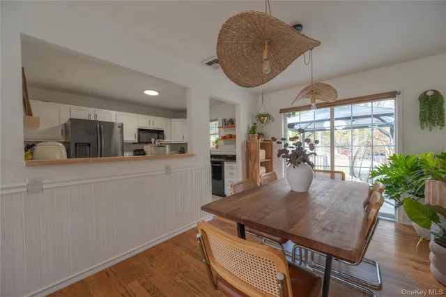 a kitchen with stainless steel appliances granite countertop a stove a refrigerator a sink a dining table and chairs with wooden floor