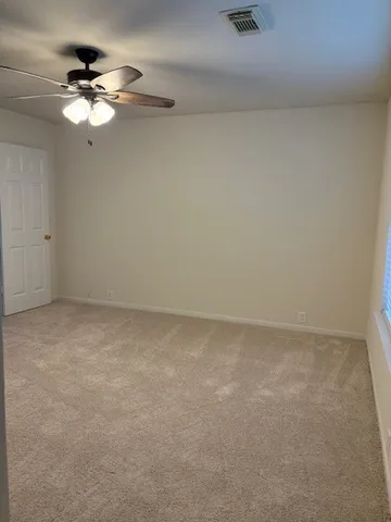 an empty room with a chandelier fan and windows