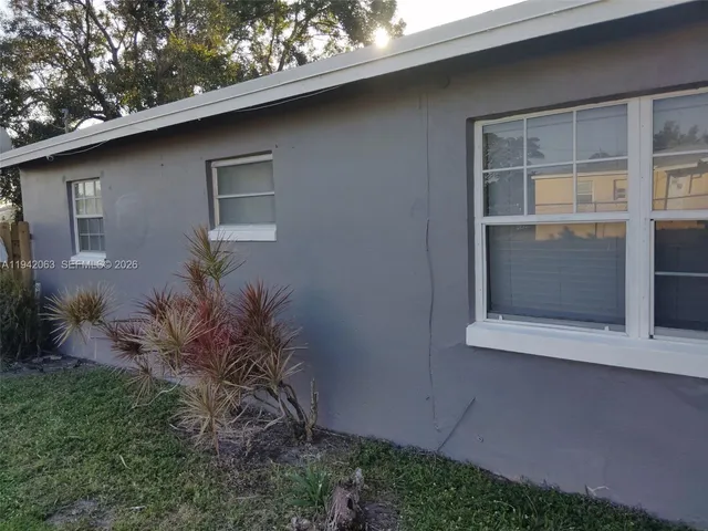 a backyard of a house with plants and large tree