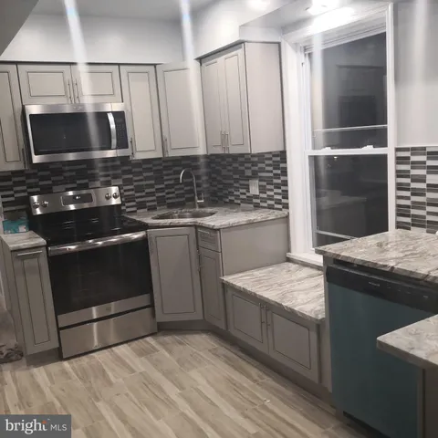 a kitchen with kitchen island granite countertop a stove and a sink