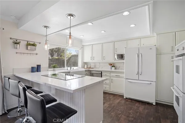 a kitchen with stainless steel appliances kitchen island granite countertop a table chairs sink and cabinets