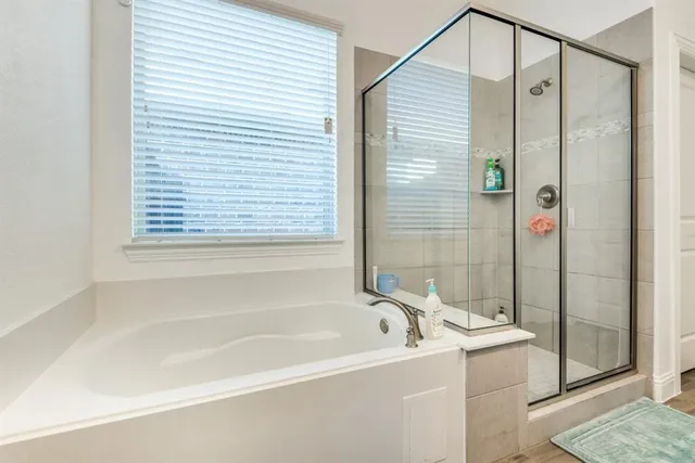 a bathroom with a sink double vanity granite tub shower and a mirror
