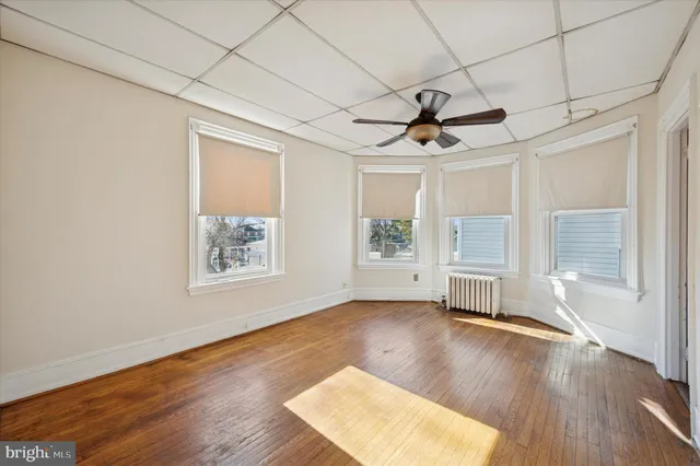 a view of empty room with wooden floor and fan