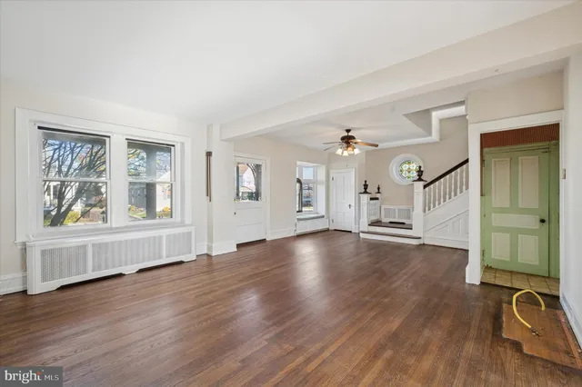 a view of an empty room with window and wooden floor