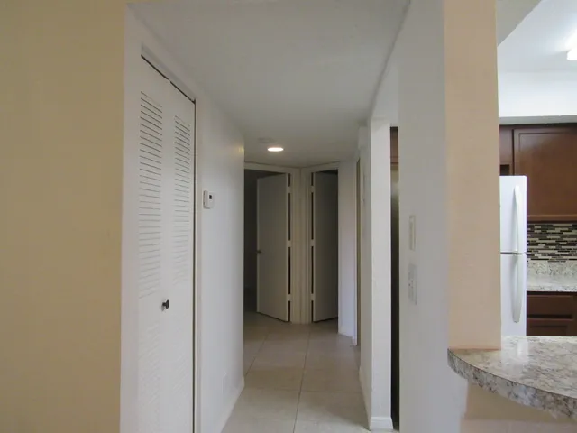 a view of a hallway with granite countertop a refrigerator and a sink