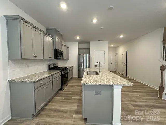 a large kitchen with granite countertop a large counter top stainless steel appliances and cabinets