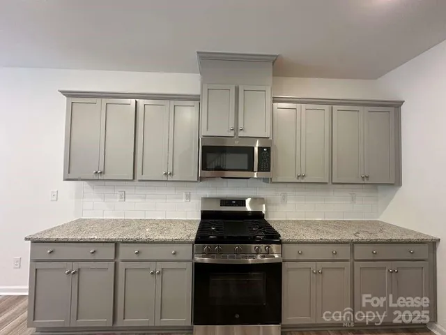 a kitchen with granite countertop white cabinets and black appliances