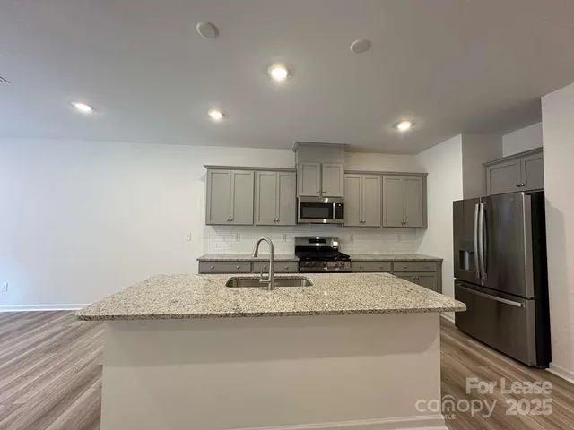 a kitchen with stainless steel appliances granite countertop a refrigerator a sink a stove a microwave and island