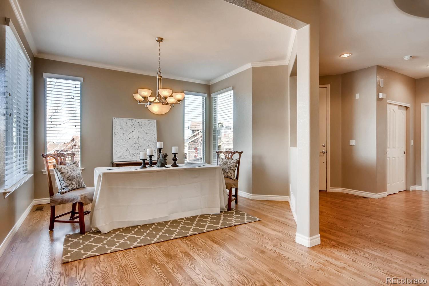 10951 Bluegate Way Highlands Ranch, CO 80130 - Photo 5 of 27 a living room with a dining table wooden floor and a chandelier