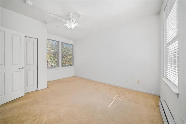 an empty room with windows and fan